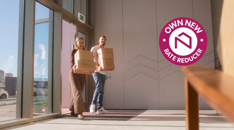 Smiling couple walking into The Dials apartment lobby with moving boxes.