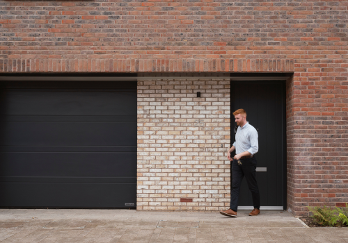 Young male smiling in smart casual clothing leaving the house with keys in his hand.