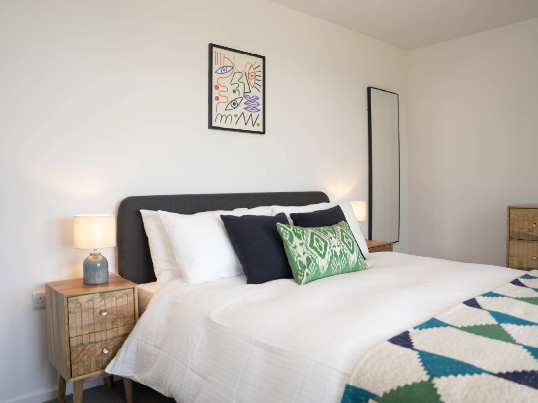 Close up of double bed and side tables in a large bedroom in a home at Brabazon, Bristol. 
