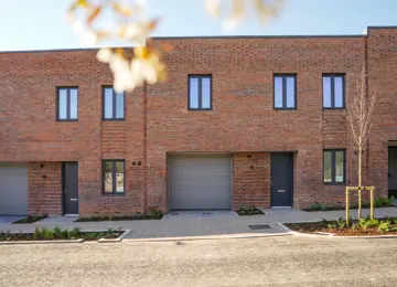 The Prier, a modern brick townhouse featuring picture windows and an enclosed carport, set in a landscaped street at Brabazon, Bristol. 