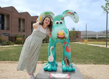Local artist Hannah Bone standing with her Gromit sculpture: 'The Birds' on The Green at Brabazon, Bristol 