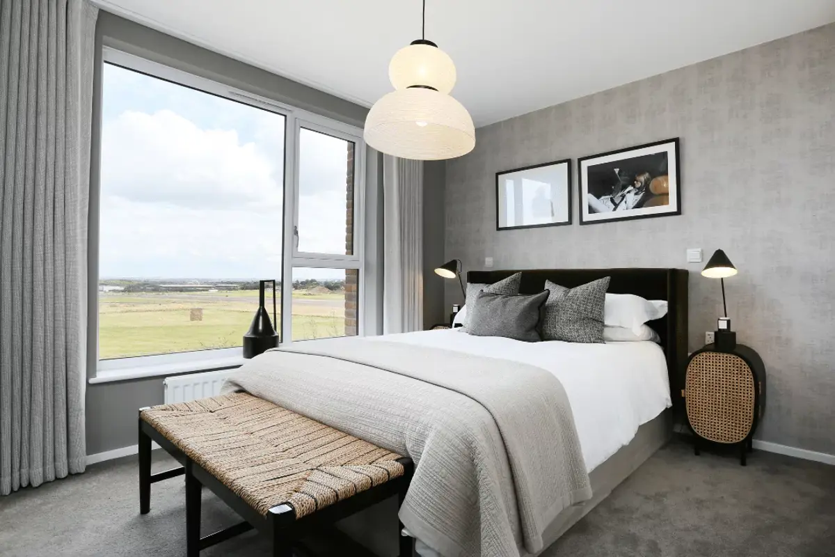 Principal bedroom flooded with natural light from expansive window, complemented by stylish furnishings.