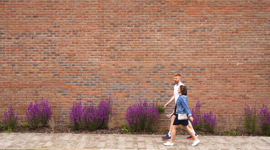 Male and female walking in front of a red brick house at Brabazon.