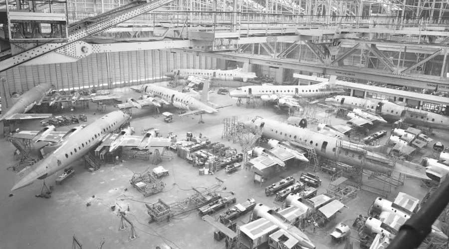 Black and white image of a large aircraft assembly hangar at Filton Airfield, showcasing multiple partially constructed airplanes. Workers and equipment are scattered across the floor.