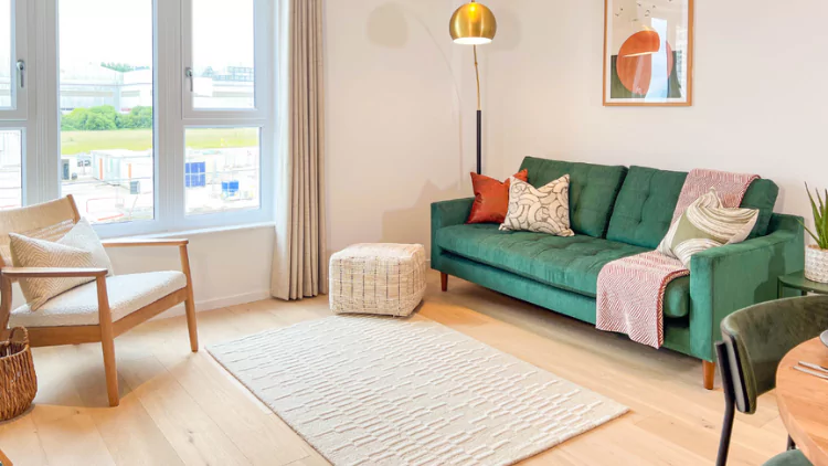 Open plan living room featuring a bold green sofa in an apartment at The Dials.