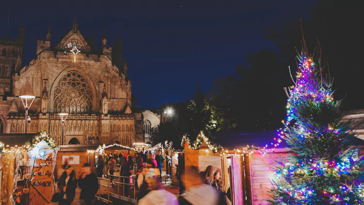 Exeter Christmas market featuring stalls, twinkly lights and a decorative Christmas tree.