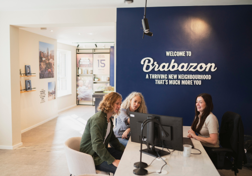Mother and son sitting at a desk with a New Homes Consultant at the Sales Centre at Brabazon.