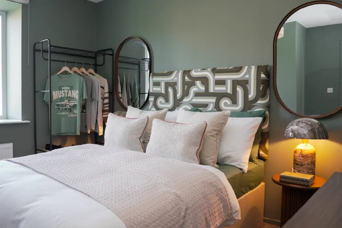 Cozy and modern secondary bedroom at Brabazon, with white bedding and a cool teal wallpaper. 