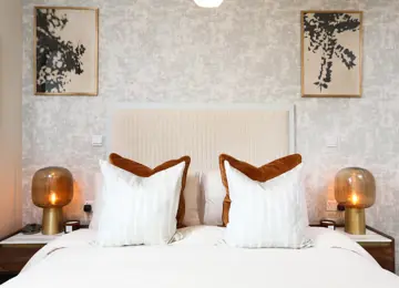 Burnt orange decor and matching bedside tables compliment this apartment primary bedroom.