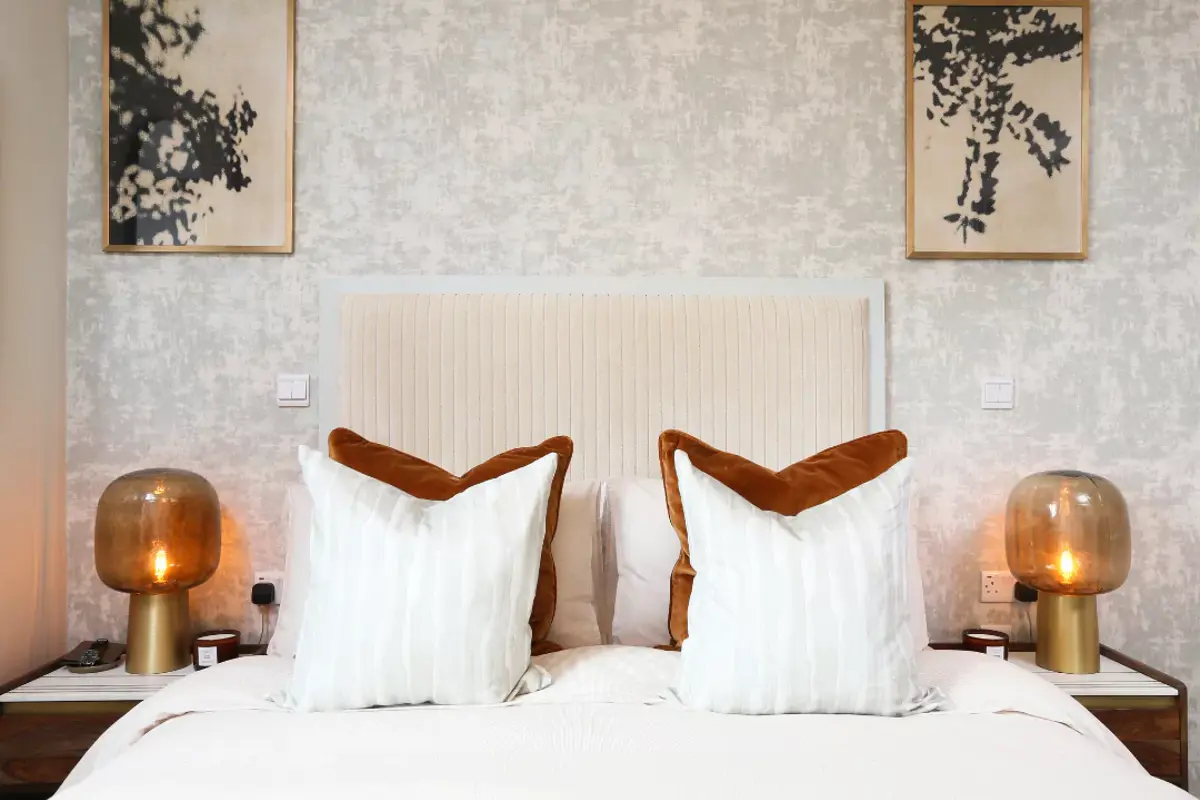 Burnt orange decor and matching bedside tables compliment this apartment primary bedroom.